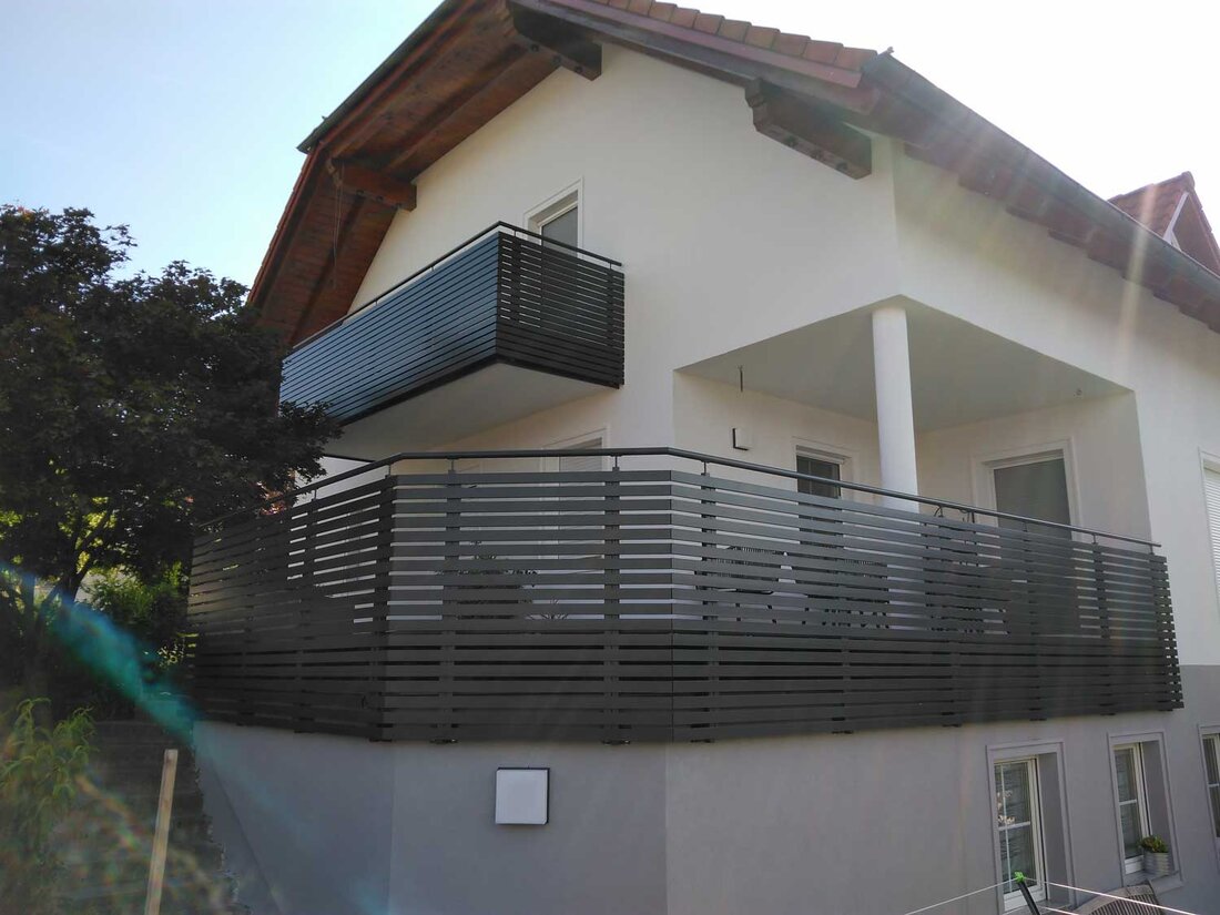 Außenansicht eines Hauser mit schwarzem Geländer bei Terrasse und Balkon